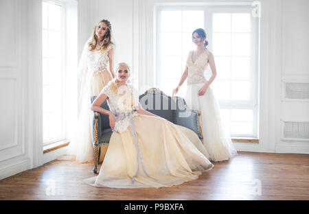 Drei junge Frauen in der Nähe der Fenster tragen Brautkleider Stockfoto