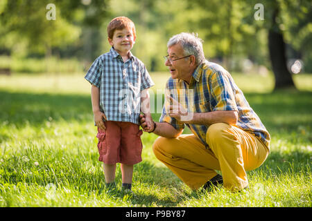 Großvater und Enkel sprechen in Park Stockfoto
