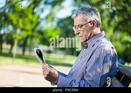 Portrait von älteren Mann lesen Zeitung in Park Stockfoto