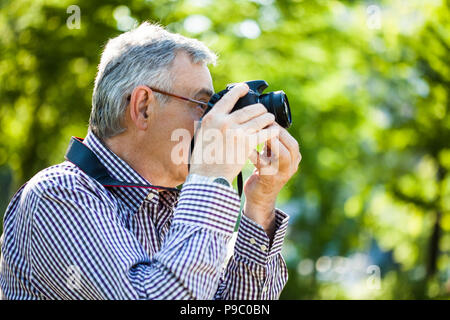 Älterer Mann ist Fotografieren in Park Stockfoto