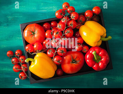 Sortierte Tomaten und Paprika in Holzkiste Stockfoto