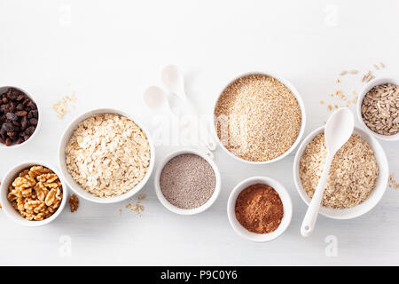 Abwechslungsreiche Auswahl von unverarbeitetem Getreide und Nüsse zum Frühstück. Haferflocken Flocken und Stahl schneiden, Gerste, Nussbaum, Chia, Rosinen. Gesunde Zutaten Stockfoto