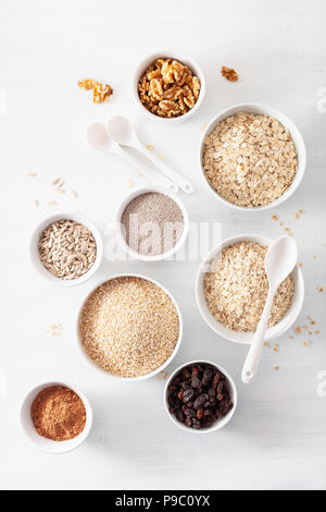 Abwechslungsreiche Auswahl von unverarbeitetem Getreide und Nüsse zum Frühstück. Haferflocken Flocken und Stahl schneiden, Gerste, Nussbaum, Chia, Rosinen. Gesunde Zutaten Stockfoto