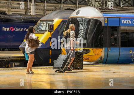 Mann und Frau entlang eine Plattform am Londoner Bahnhof Paddington und dem Heathrow Express an Bord Stockfoto