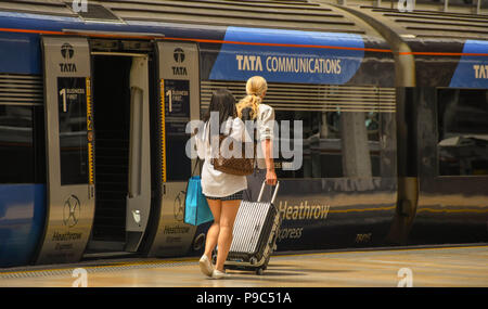 Fahrgäste entlang eine Plattform am Londoner Bahnhof Paddington und dem Heathrow Express an Bord Stockfoto