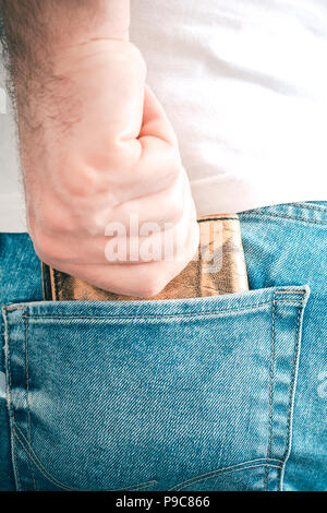 Männliche Hand packte einen braunen Leder Geldbörse in der Gesäßtasche der Jeans Hose Stockfoto