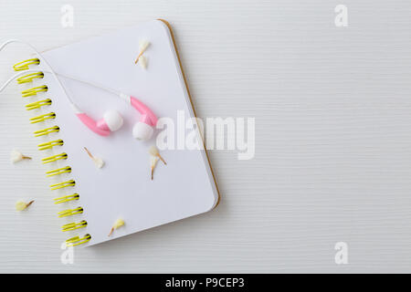 Pink Kopfhörer und Notebook mit Blumen auf weißem Hintergrund, Ansicht von oben Stockfoto