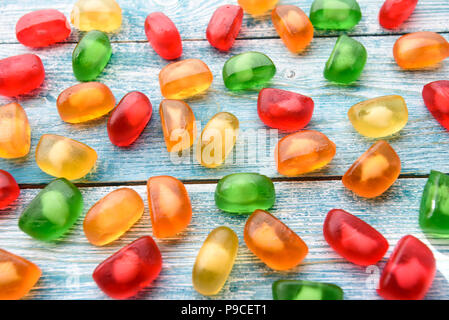 Bunte Jelly Bonbons auf blauem Hintergrund Holz verstreut Stockfoto