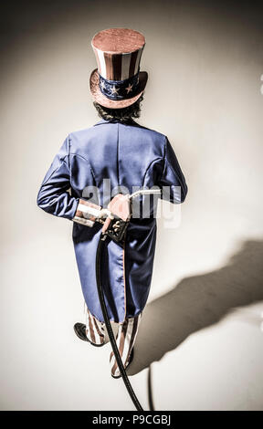 Uncle Sam-Figur von hinten mit einem Benzin pumpe Düse hinter seinem Rücken gesehen. Stockfoto