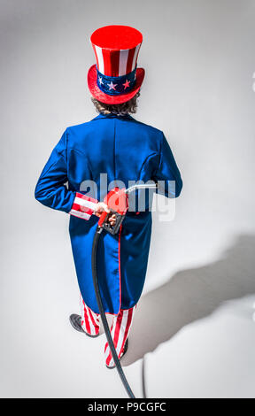 Uncle Sam-Figur von hinten mit einem Benzin pumpe Düse hinter seinem Rücken gesehen. Stockfoto