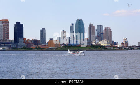 Ein Wasserflugzeug landet in New York City's East River mit Jägern zeigen, Queens im Hintergrund Stockfoto