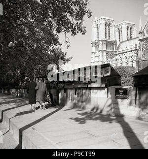 1950, historische, Sommer und einen Blick auf die Pariser "bouquinistes" oder buchen Sie Stände, die sich am linken Ufer der Seine, Quai de Montebello, Paris, Frankreich. Diese Open-air-Händler verkaufen Gebrauchte und antiquarische Bücher sind eine sehr beliebte Teil der Stadt. Die berühmte Kathedrale Notre-Dame können im Hintergrund gesehen werden. Stockfoto