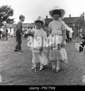 1960, historische, außerhalb an einem englischen Dorffest, zwei junge Mädchen in einem Feld stehend tragen Kostüme, ein wenig Bo-Peep, eine junge shepherdress, ein Charakter von einem populären Engllish Sprache nursey Reim. Stockfoto