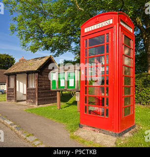 Traditionelle britische rote Telefonzelle, Bushaltestelle und Dorf Aushang Szene an Lurgashall, West Sussex, England, Großbritannien Stockfoto