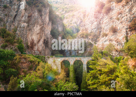 Warme Bild des schönen alten Brücke im Canyon durch Bäume bei Sonnenuntergang umgeben mit Sonne durch, Sorrento, Kampanien, Italien Stockfoto