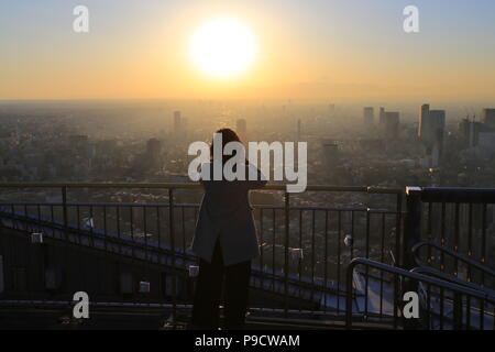 Office lady beobachten Sie den Sonnenuntergang auf der Oberseite der Wolkenkratzer in Tokio Stockfoto