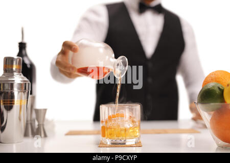 Barkeeper gießt Whiskey in einem Glas auf weißem Hintergrund Stockfoto