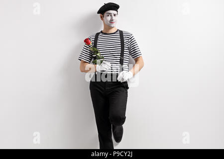 Mime mit einer Rose Blume gegen eine Wand gelehnt Stockfoto