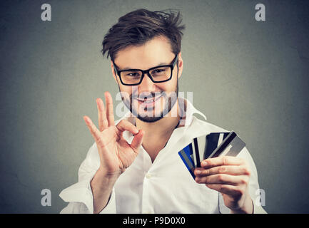 Inhalt Geschäftsmann in Gläser holding Haufen von Kreditkarten und mit OK Geste zur Genehmigung bank Wahl Stockfoto
