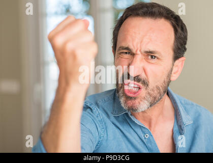 Gut aussehender Mann mittleren Alters genervt und frustriert schrie mit Zorn, verrückt und schreien mit erhobener Hand, Wut Konzept Stockfoto