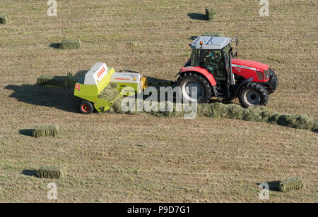 Landwirt in Swaledale, North Yorkshire, Heuballen, mit einem Massey Ferguson 5470 und ein CLAAS Rundballenpresse. Stockfoto