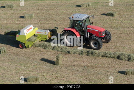 Landwirt in Swaledale, North Yorkshire, Heuballen, mit einem Massey Ferguson 5470 und ein CLAAS Rundballenpresse. Stockfoto