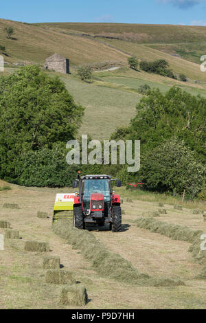 Landwirt in Swaledale, North Yorkshire, Heuballen, mit einem Massey Ferguson 5470 und ein CLAAS Rundballenpresse. Stockfoto