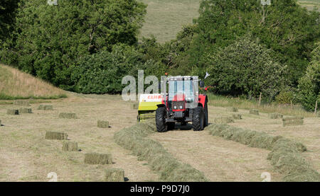 Landwirt in Swaledale, North Yorkshire, Heuballen, mit einem Massey Ferguson 5470 und ein CLAAS Rundballenpresse. Stockfoto