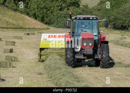 Landwirt in Swaledale, North Yorkshire, Heuballen, mit einem Massey Ferguson 5470 und ein CLAAS Rundballenpresse. Stockfoto