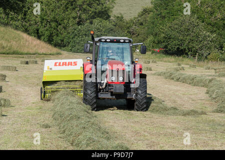 Landwirt in Swaledale, North Yorkshire, Heuballen, mit einem Massey Ferguson 5470 und ein CLAAS Rundballenpresse. Stockfoto