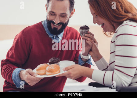 Glückliches Paar lachend, während bei der Kuchen auf dem Teller suchen Stockfoto
