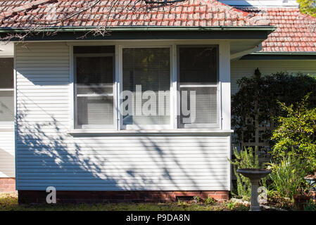 Die Front eines im Stil der 50er und weatherboard Ziegeldach in Sydney mit 2 Doppel-hung Holzfenster typisch weiß gestrichen. Stockfoto