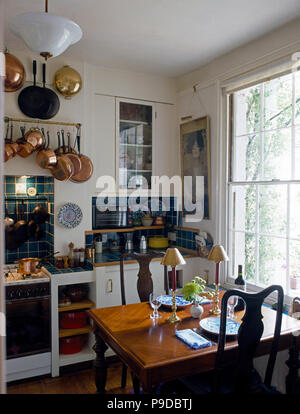 Kleiner Tisch für das Mittagessen in einem Stadthaus Küche mit Vintage Kupfer Pfannen auf einem Gestell über dem Herd set Stockfoto