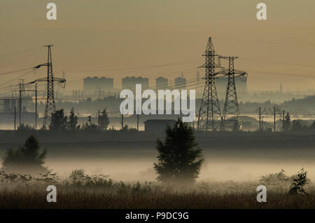 Nebel über Felder und Türme von Stromleitungen am Rande der Stadt auf dem Hintergrund von Stromleitungen Stockfoto