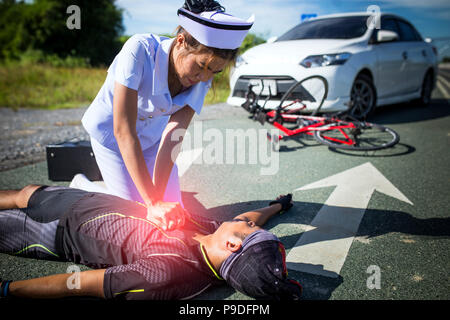 Weibliche Krankenschwester helfen Not CRP auf dem Fahrrad Mann bei einem Unfall Stockfoto