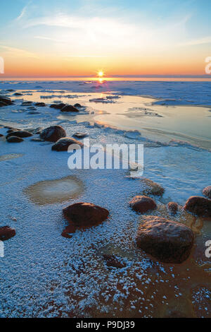 Sonnenuntergang in das gefrorene Meer mit Raureif und Steine am Strand der Ostsee Stockfoto