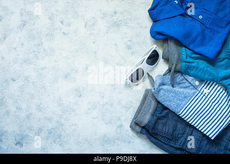 Kind Kleidung - Jeans, Polo, Shorts und Turnschuhen Draufsicht auf Stein Hintergrund. Mode Beauty Hintergrund. Modernes Aussehen. Flach kopieren. Stockfoto