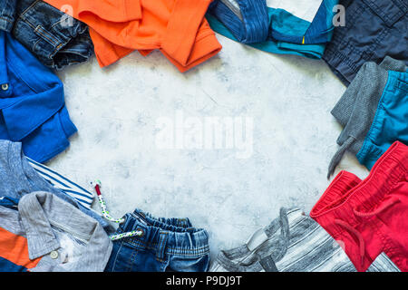 Kind Kleidung - Jeans, Polo, Shorts und Turnschuhen Draufsicht auf Stein Hintergrund. Mode Beauty Hintergrund. Modernes Aussehen. Flach kopieren. Stockfoto