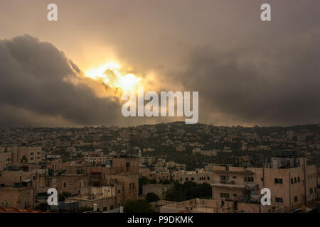 Ein Sturm macht sich über Bethlehem, Palästina, mit der Sonne kurz durch die Wolken über den Konflikt enträtselt Stadt brechen Stockfoto