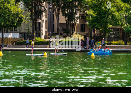 Stand up paddleboarding und ein Tretboot auf dem Bassin de la Villette in Paris, Frankreich Stockfoto