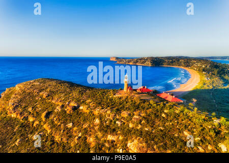 Barrenjoye Head Lighthouse hoch über dem nördlichen Strände Küste von Sydney über Palm Beach auf einem hellen ruhigen Morgen leuchtet durch die warme Sonne Licht. Stockfoto