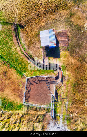 Der Eingang und Ladebereich an entfernten Land Rinder Farm auf einer Ebene mit Weide und Gras in die Antenne vertikal von oben nach unten Blick auf eine Halle mit Tor und Stockfoto