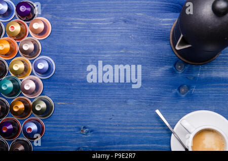 Espresso, Espressomaschine und Kaffeekapseln auf einem blauen Hintergrund aus Holz Stockfoto