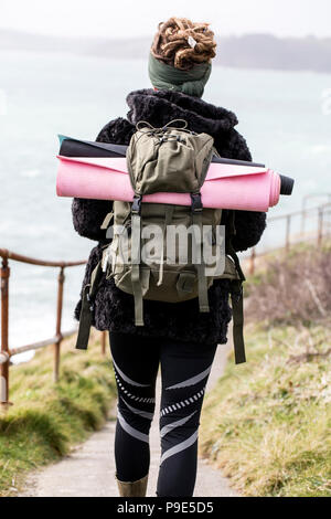 Ansicht der Rückseite des junge Frau mit braunen Haaren und Dreadlocks tragen Rucksack, entlang der Küsten Wanderweg. Stockfoto