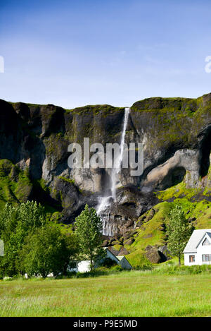 Eine isländische Wasserfall mit Haus darunter Stockfoto