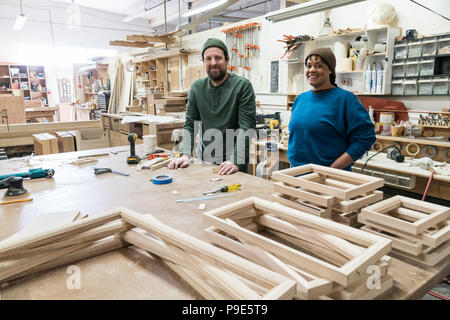 Porträt von einem Team aus zwei gemischten Rennen der männlichen und weiblichen Tischler in einem großen Holz verarbeitenden Fabrik. Stockfoto