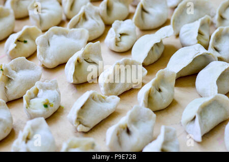 Chinesische rohe Klöße auf Holzbrett. Die Klöße, Jiaozi in Chinesisch, beliebt für Chinese New Year Festival genannt. Stockfoto