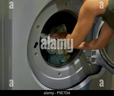 Mädchen lädt die Waschmaschine im Hauswirtschaftsraum Stockfoto