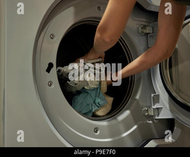 Mädchen lädt die Waschmaschine im Hauswirtschaftsraum Stockfoto