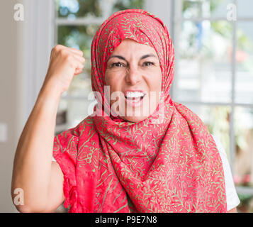 Im mittleren Alter muslimische Frau mit Kopftuch genervt und frustriert schrie mit Zorn, verrückt und schreien mit erhobener Hand, Wut Konzept Stockfoto